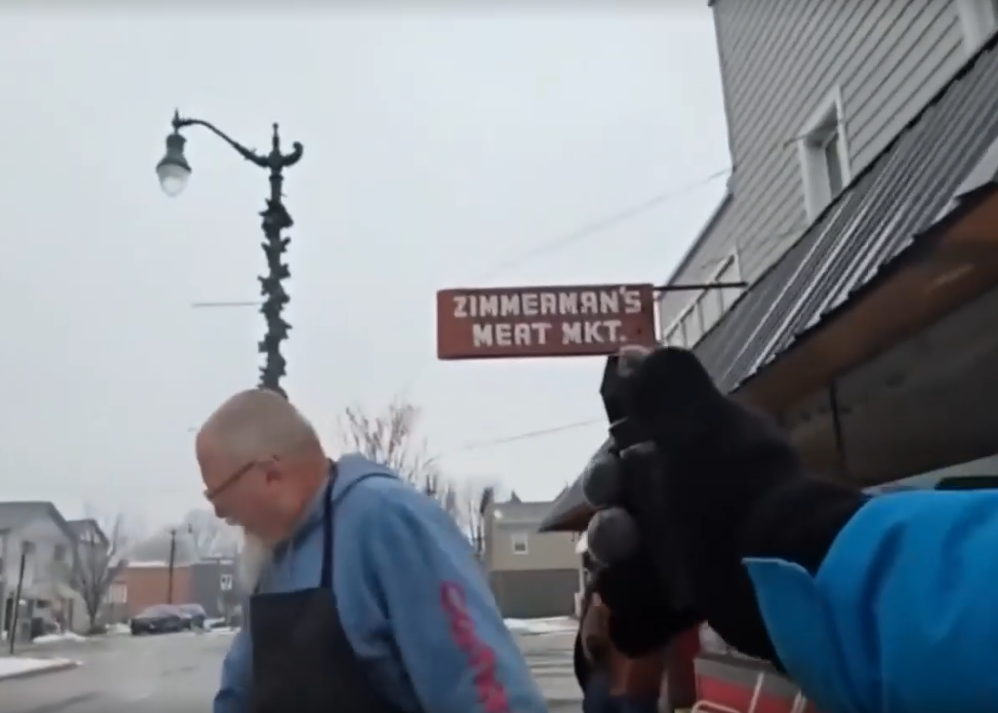 bald man wincing in pain as a stream of pepper spray shoots from a small canister held in a gloved hand
